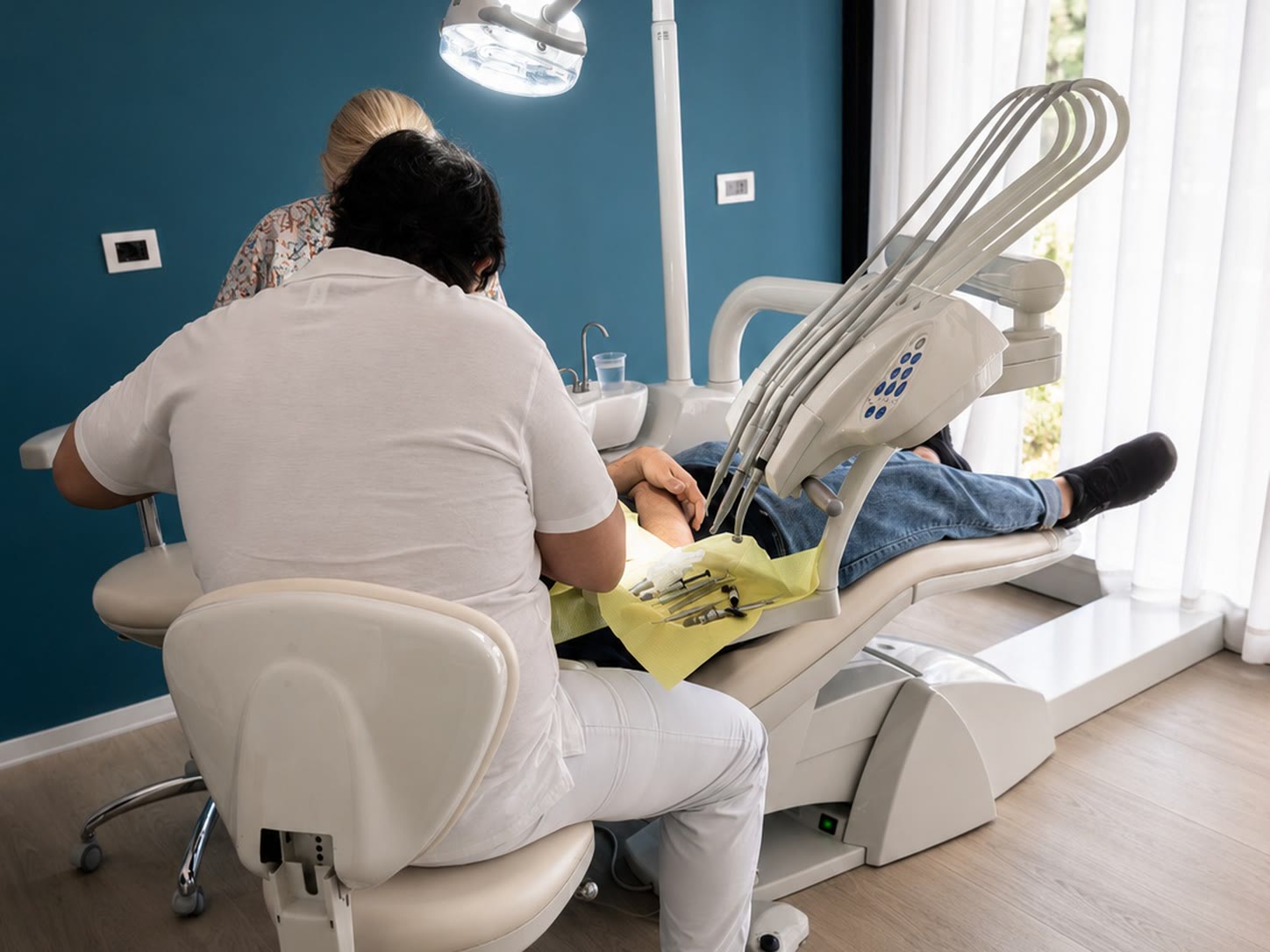 Terza scena clinica reale dello Studio Dentistico Lera: due operatori al lavoro accanto al riunito, ripresi di spalle